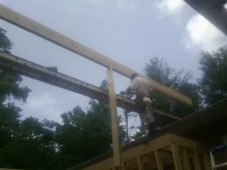 Carpenter setting a ridge beam over a new addition frame — Ice Dam Removal by Roofing Brothers in Mount Upton