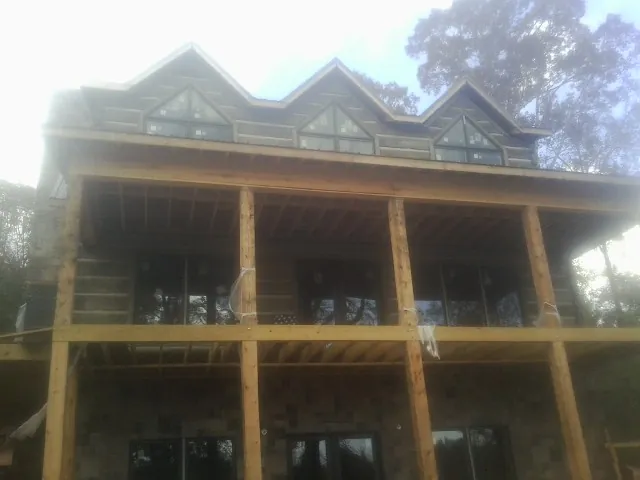 Dormers and porch framing on a large log home under construction — Roof Coating work by our crew in Mount Upton