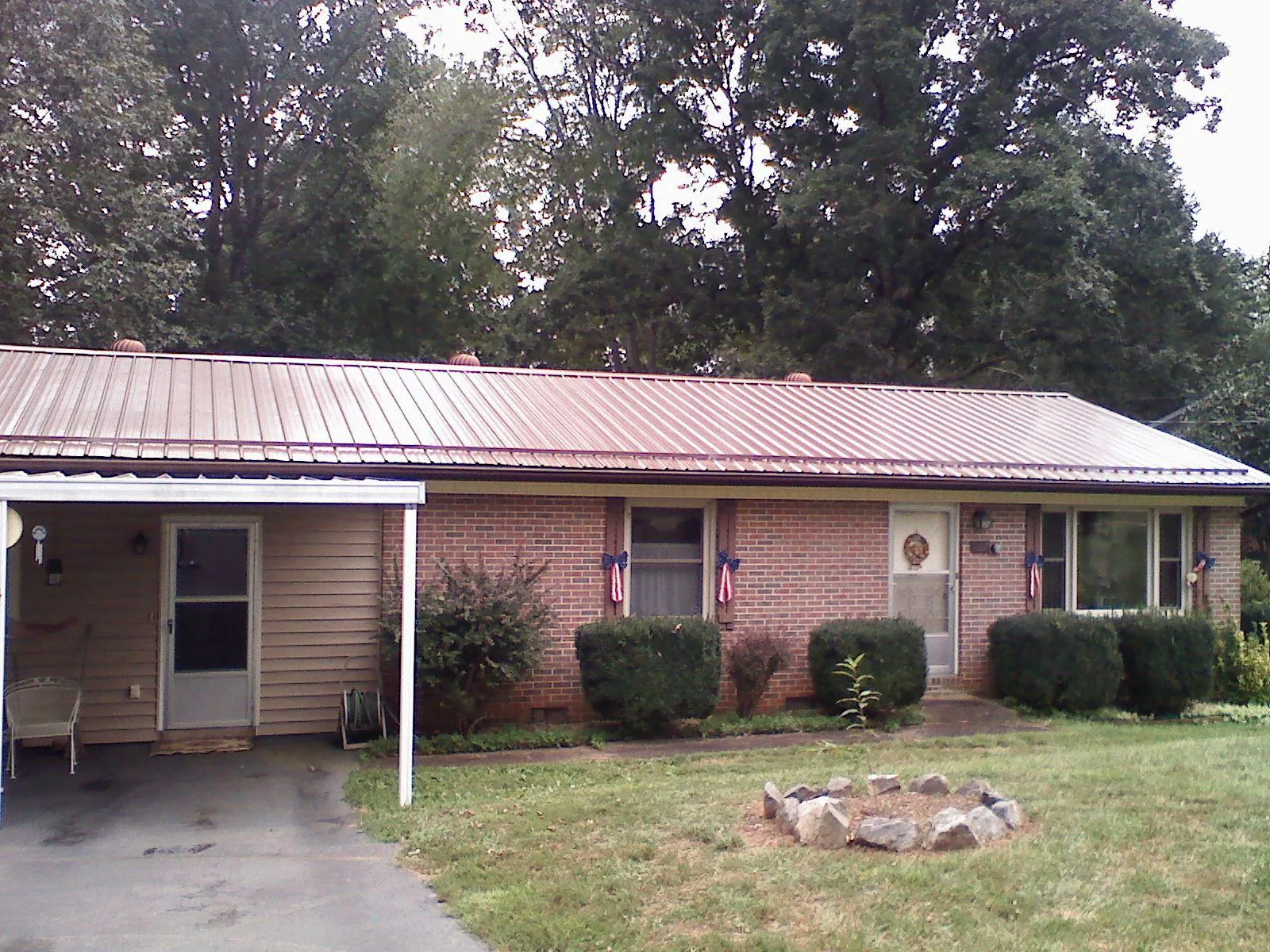 Bronze metal roof and carport on a brick ranch home — Roof Repair work by our crew in Mount Upton