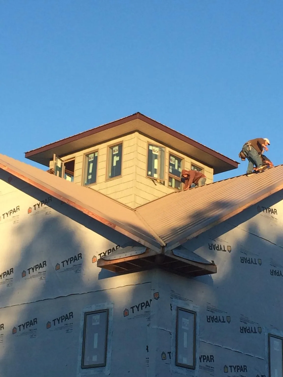 Roofers working around a rooftop cupola on a new metal roof at sunset — Roof Waterproofing in Mount Upton by Roofing Brothers